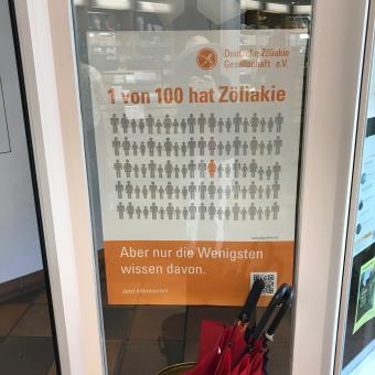 Einer von hundert hat Zöliakie, aber nur die Wenigsten wissen davon. Das zeigt das Plakat mit hundert Personen, 99 in grau, eine in orange.